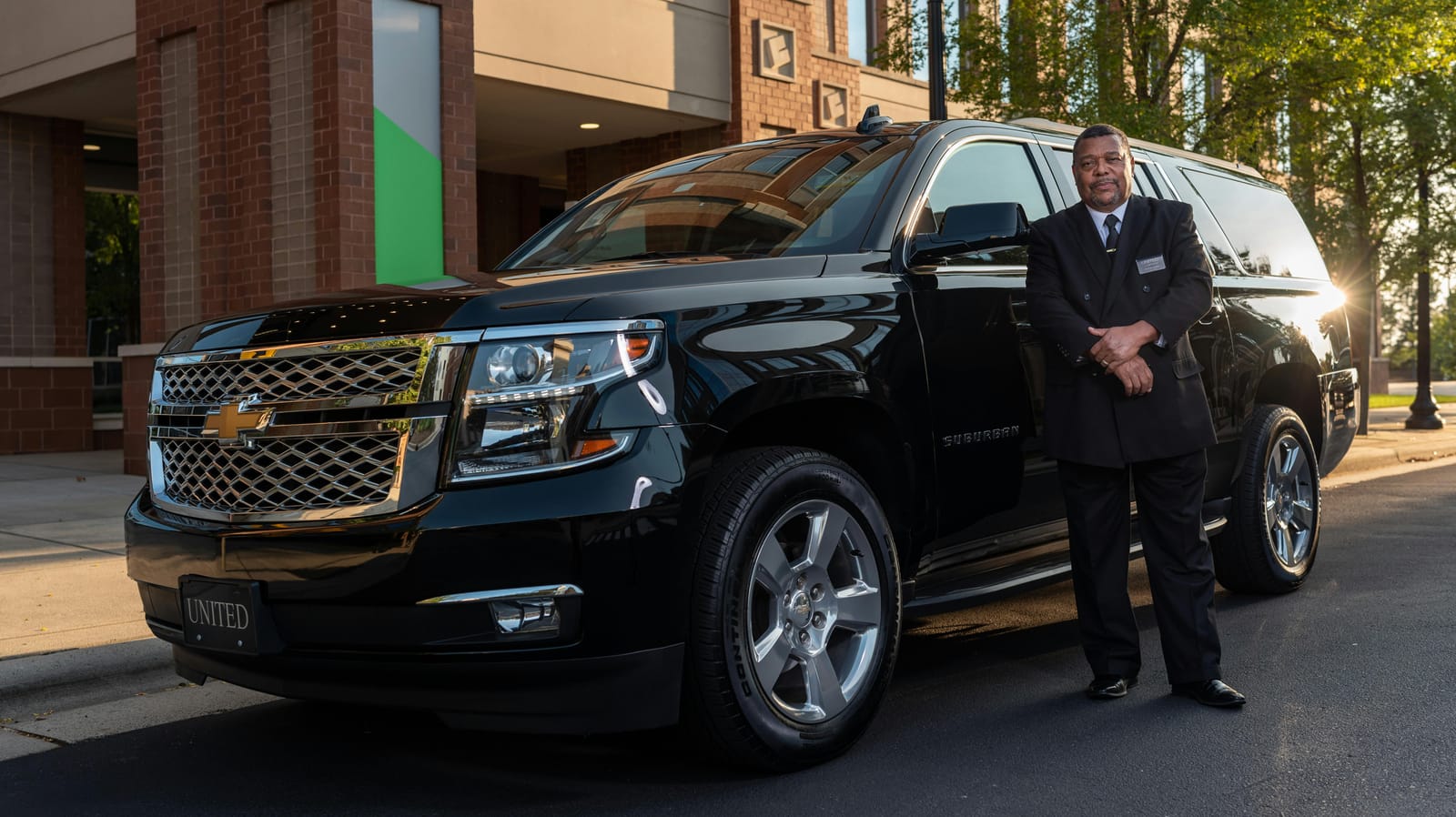 Licensed, professionally dressed BlackCarIllinois chauffeur standing beside a black SUV