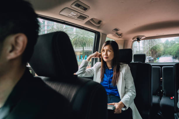 Businesswoman enjoying a comfortable ride in a chauffeur-driven car for corporate travel, focusing on luxury and convenience.