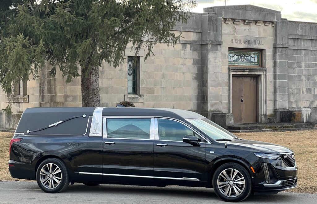 Black funeral limousine parked in front of a historic building, ideal for respectful and dignified funeral transportation services.